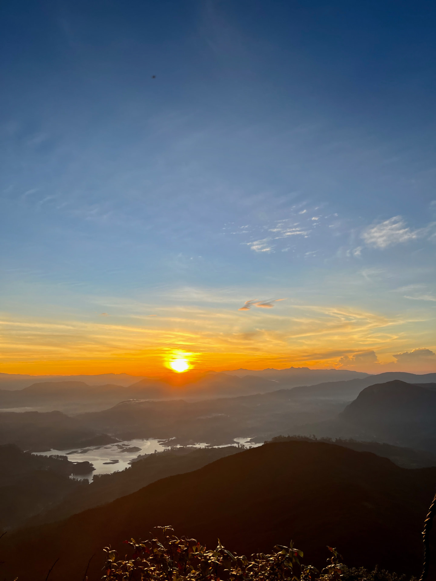 Sunrise from the summit of Sri Pada over misty mountains and a reservoir